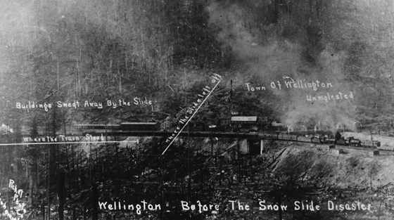 Photographie en noir et blanc pâlie d'une gare de train parsemée d'annotations écrites à la main qui indiquent où l'avalanche a frappé.